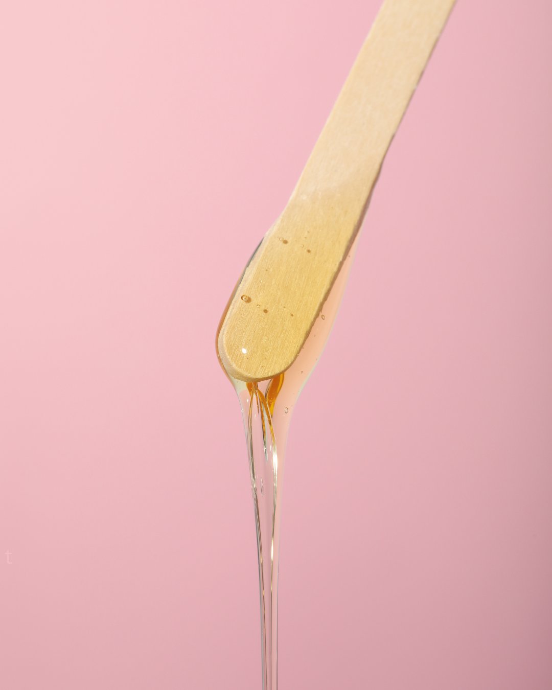 Warm wax dripping from applicator, professional Brazilian waxing service at Captivant Esthetics in Tamarac FL